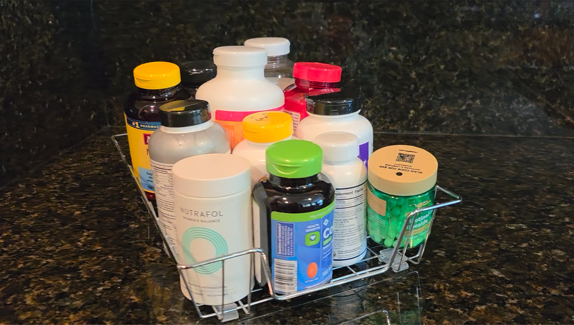 A metal basket holds assorted bottles of supplements on a dark granite countertop, reminding you that small actionable changes can transform your life.